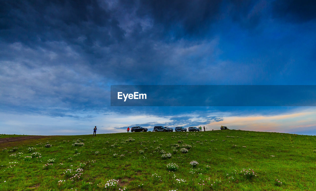 Low angle view of people with off-road vehicle against cloudy sky