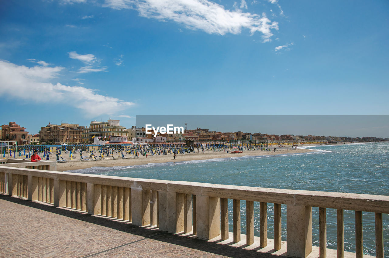 View of marble pier, with the beach and the city of ostia in italy.