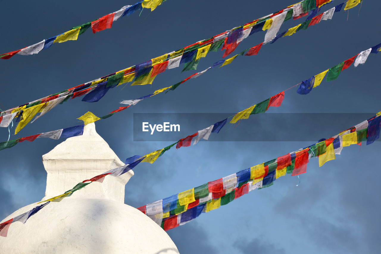 Boudhanath stupa and buddhist prayer flags against cloudy blue sky, kathmandu, nepal