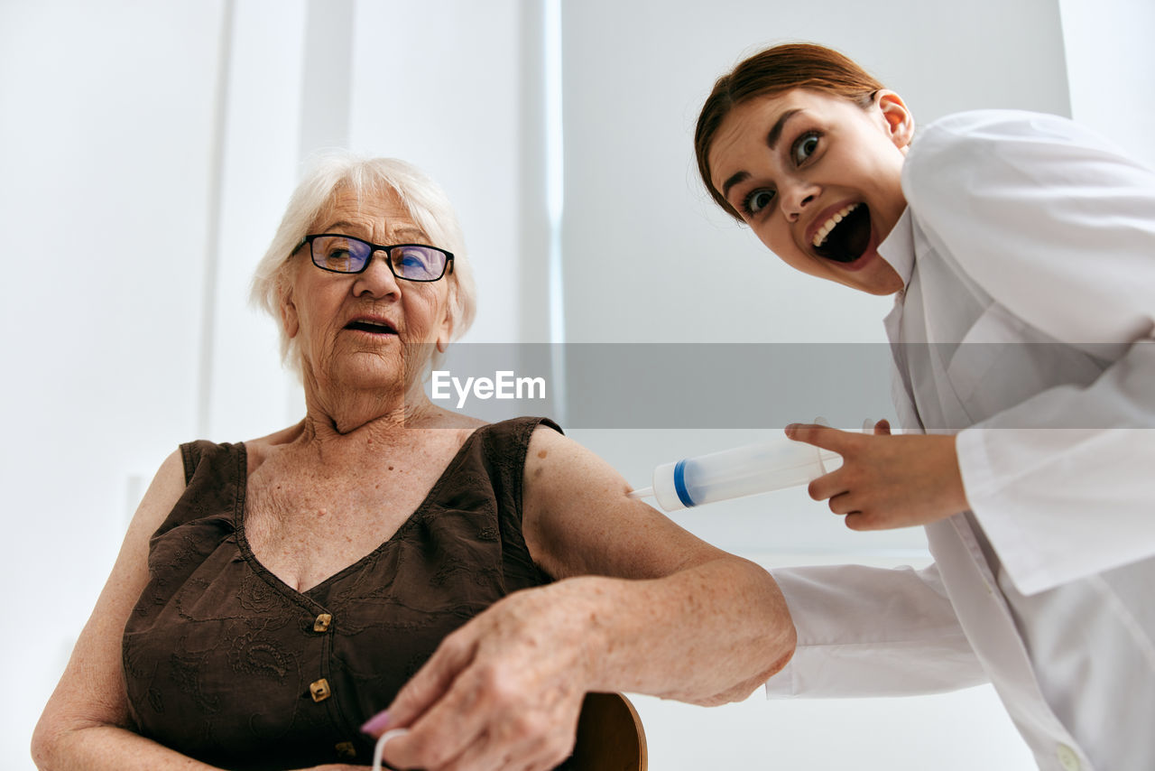 Cheerful doctor vaccinating senior woman at clinic