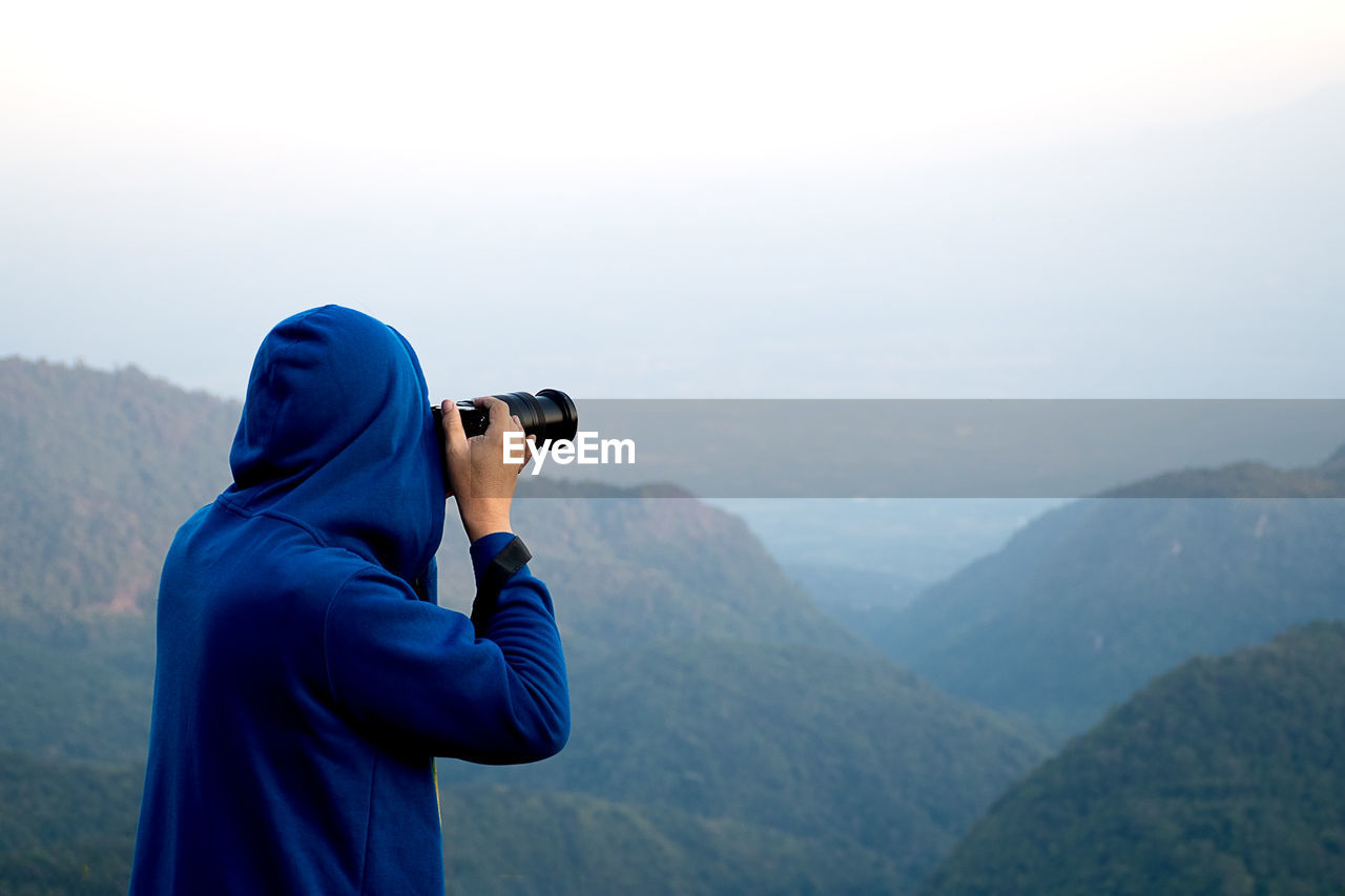 Rear view of person photographing mountains from camera