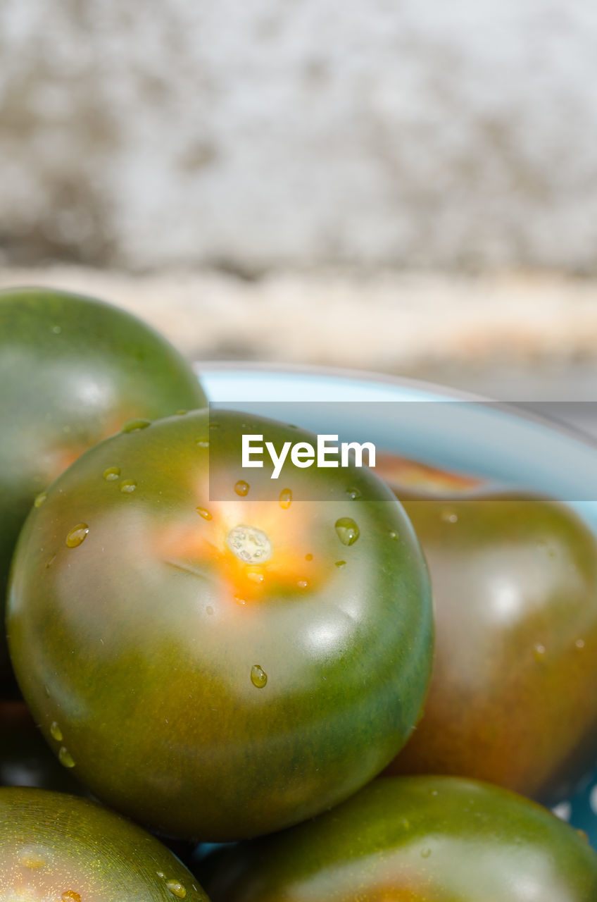 Close-up of unripe tomatoes in colander on table