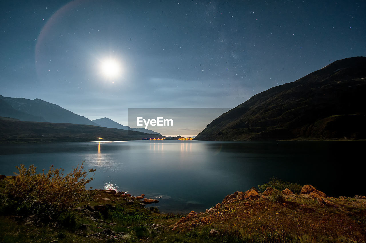 Scenic view of lake and mountains against sky at night