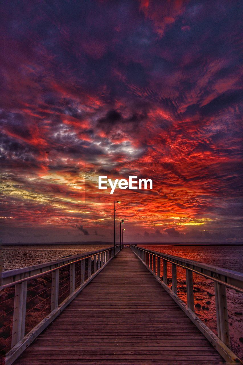 Pier over sea against sky during sunset