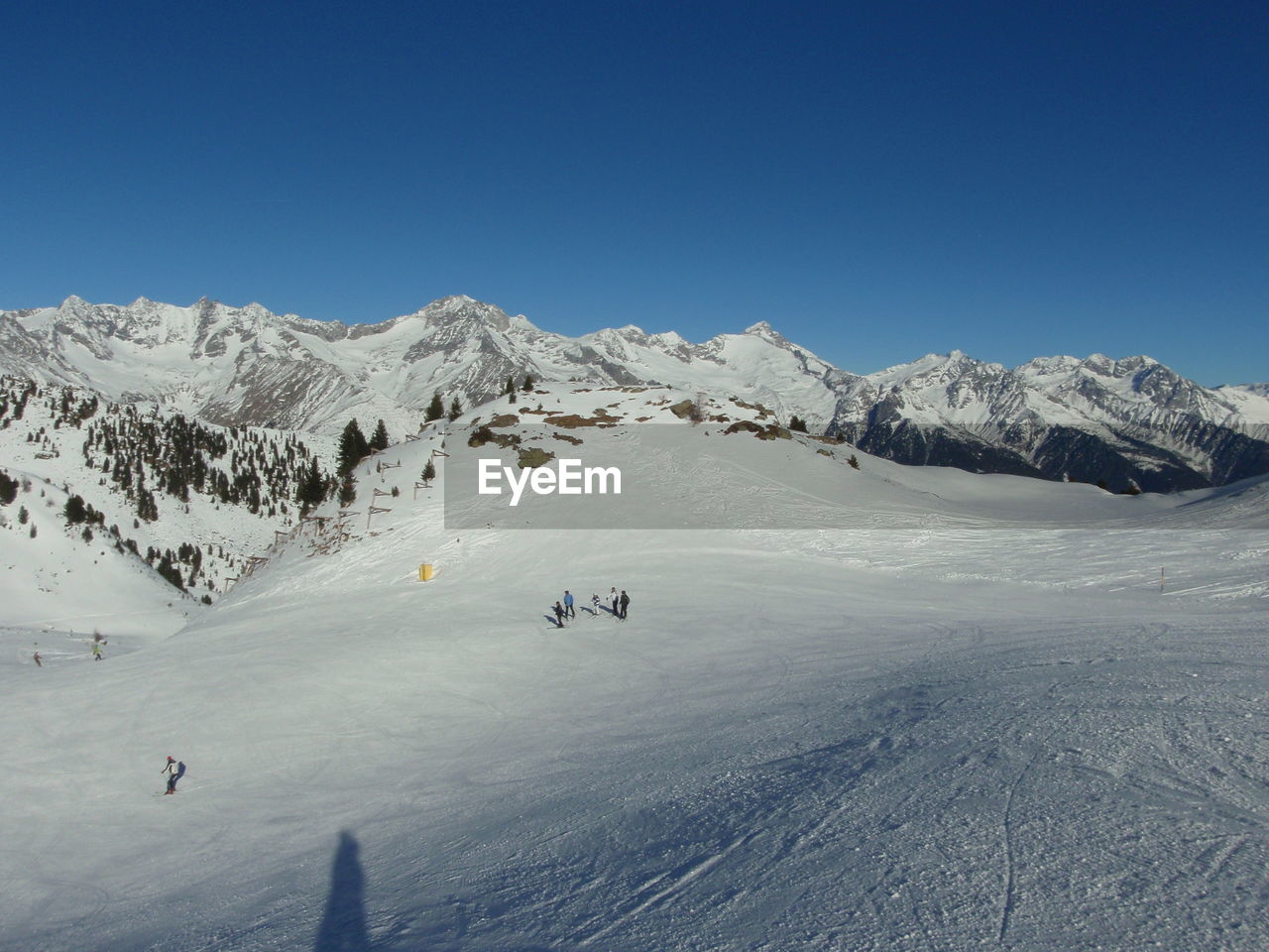 HIGH ANGLE VIEW OF PEOPLE SKIING ON SNOWCAPPED MOUNTAIN