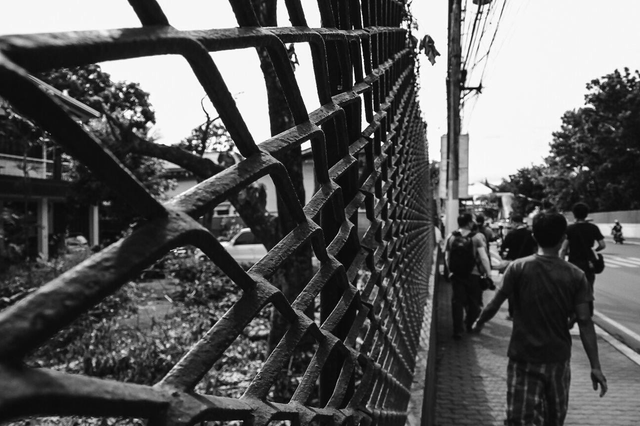 People walking on footpath by fence