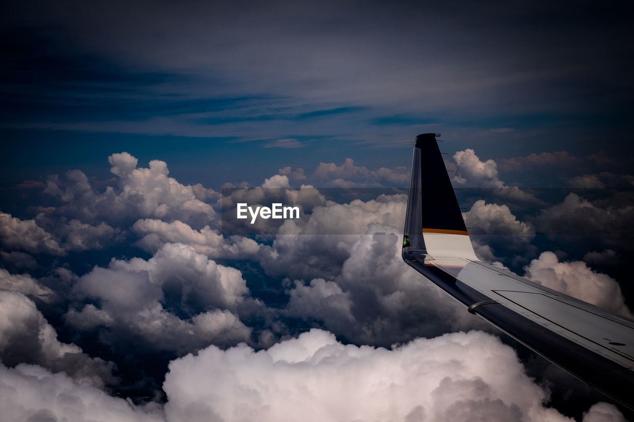 Aircraft wing against cloudy sky seen from airplane window