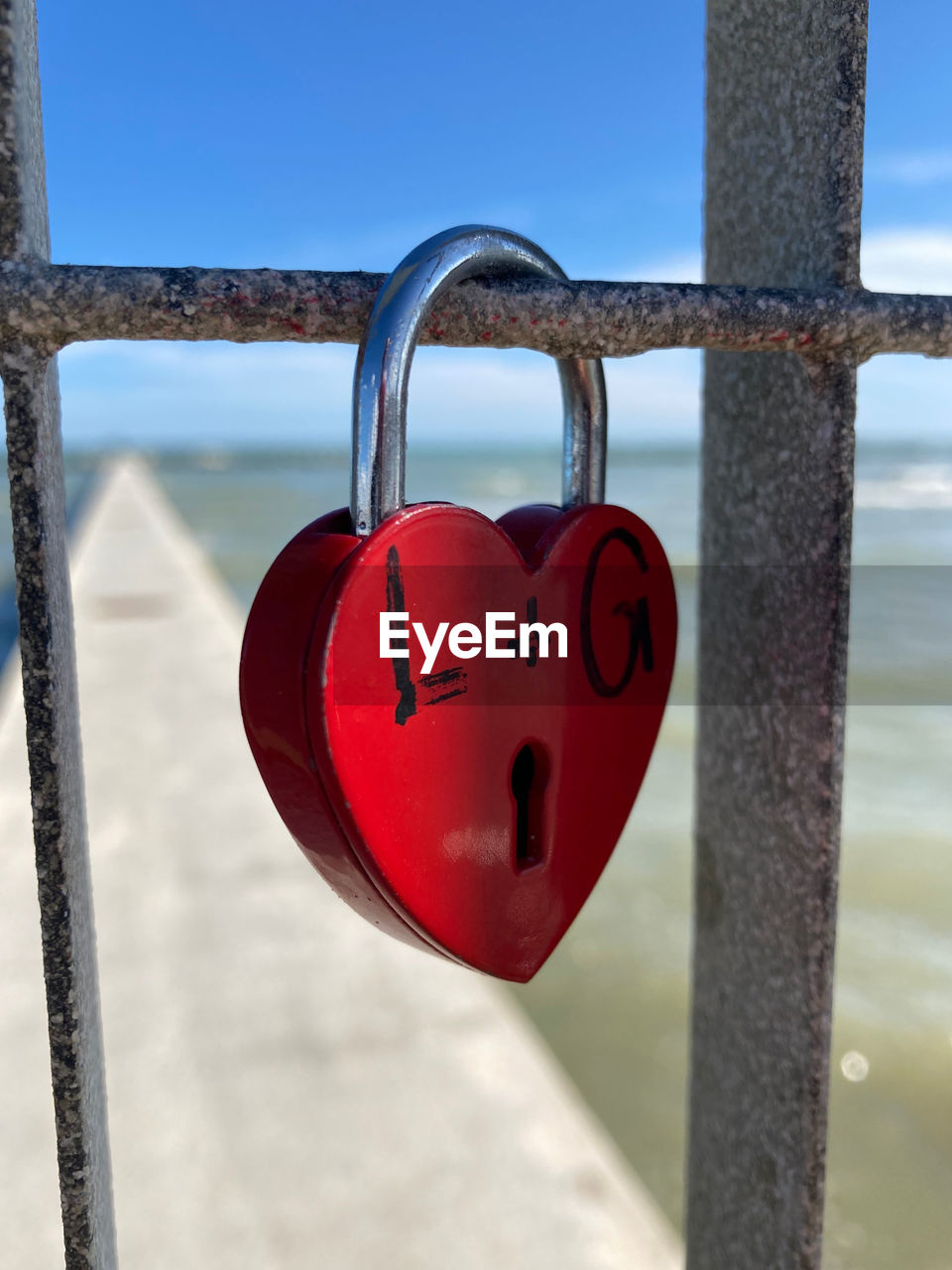 lock, love, padlock, heart shape, positive emotion, red, security, protection, emotion, metal, hanging, hope, love lock, heart, railing, romance, nature, day, blue, iron, fence, sky, close-up, outdoors, focus on foreground, water, communication, luck, architecture, symbol, gate, safe, travel destinations, rusty, lighting
