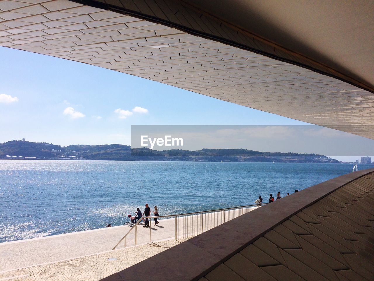 People on promenade by sea seen from bridge