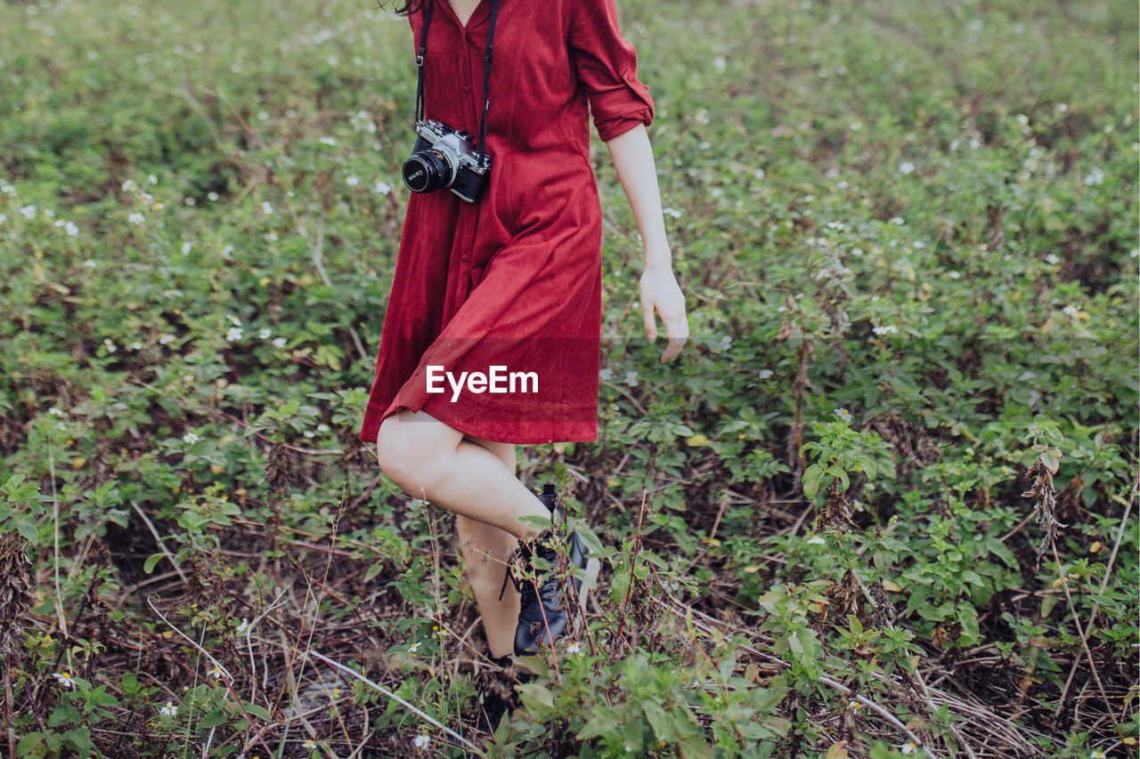 LOW SECTION OF WOMAN WALKING ON GRASSY FIELD