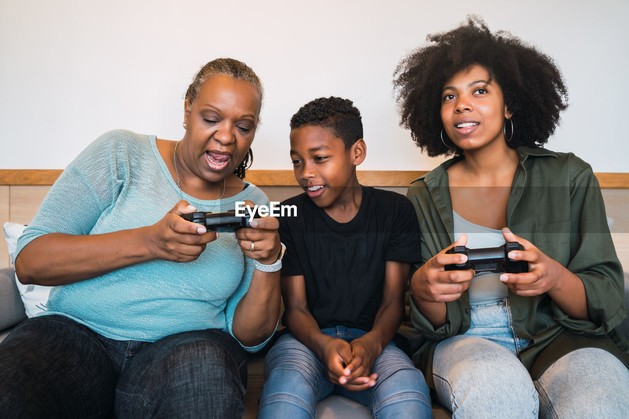 Family playing video game while sitting on sofa at home