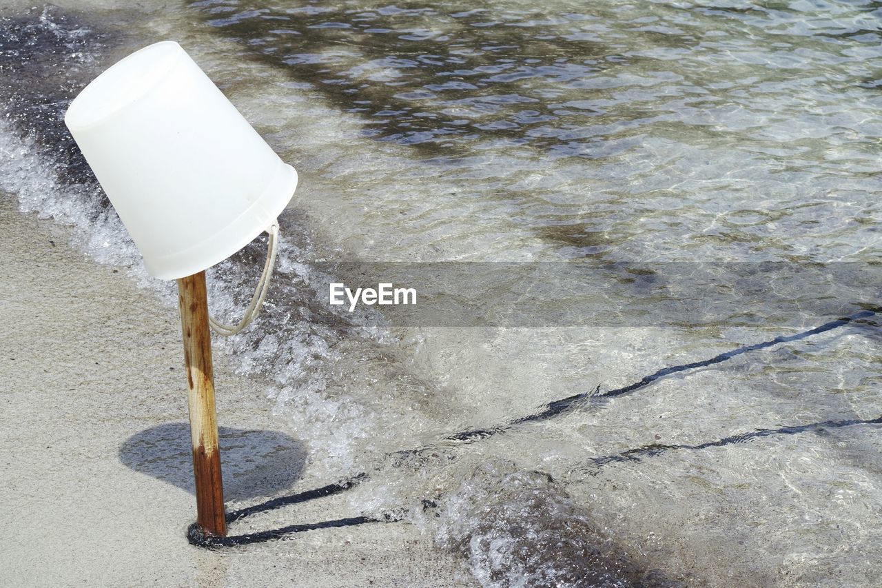 High angle view of bucket on wooden post at seashore