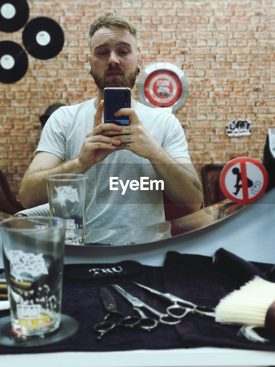 Portrait of young man taking selfie against mirror