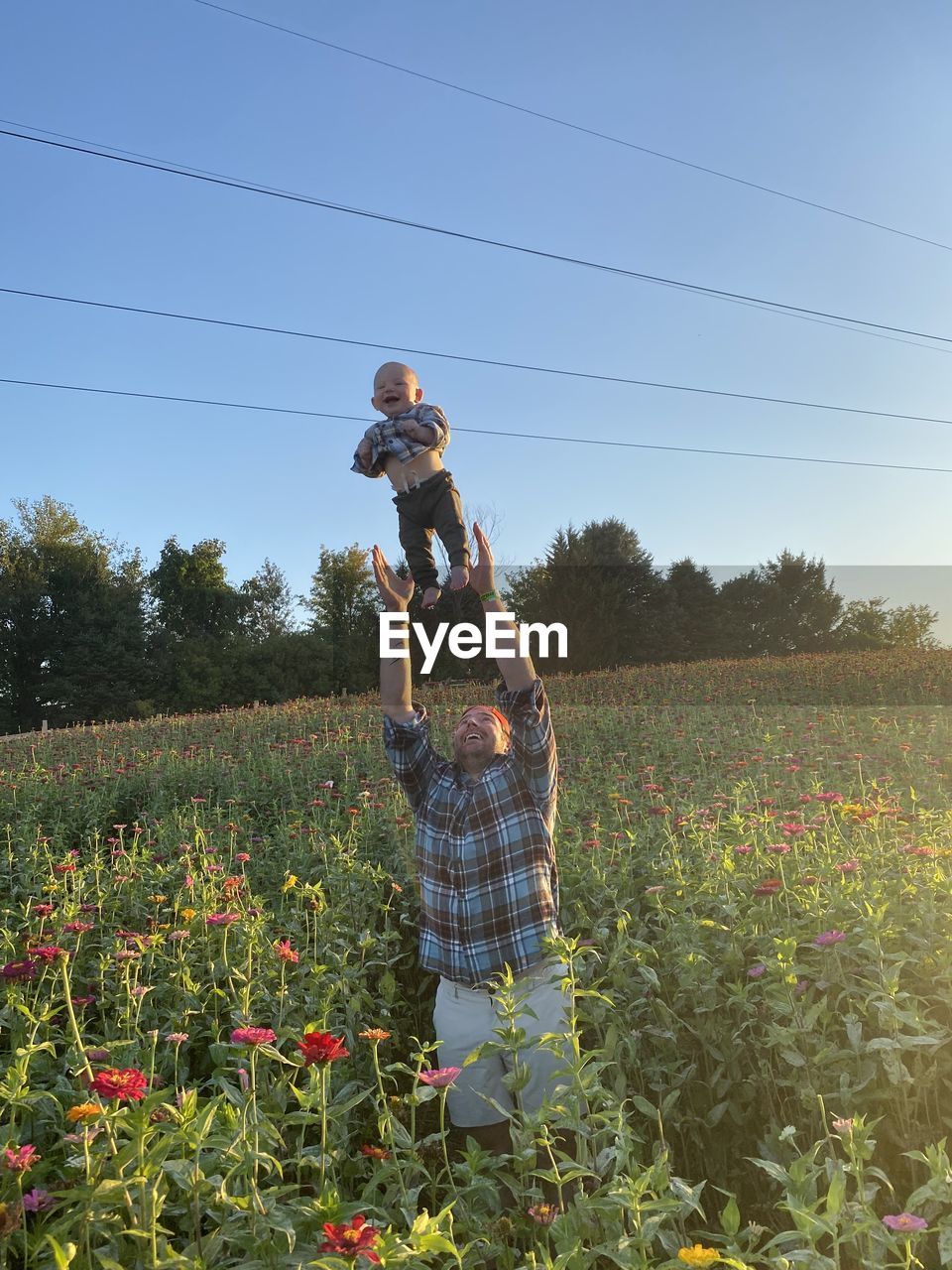 Front view of man standing on field against sky playing with his child