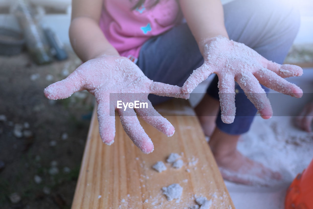 Low section of girl showing messy hands while sitting on seat