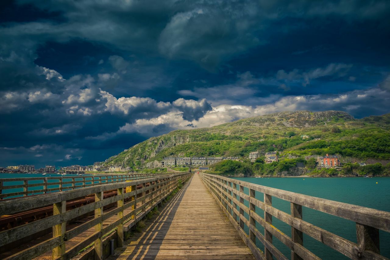 Footbridge over sea against sky