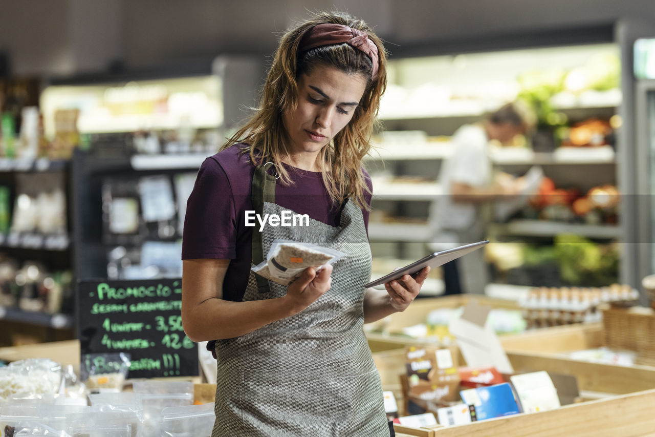 Shop owner holding tablet pc analyzing product at organic market