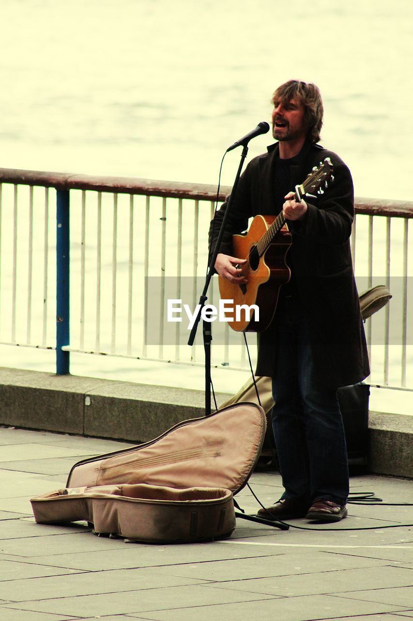 Full length of street performer playing guitar