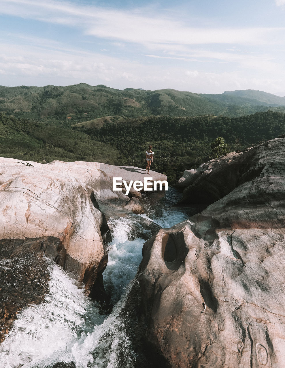 Woman standing on rock formation by river