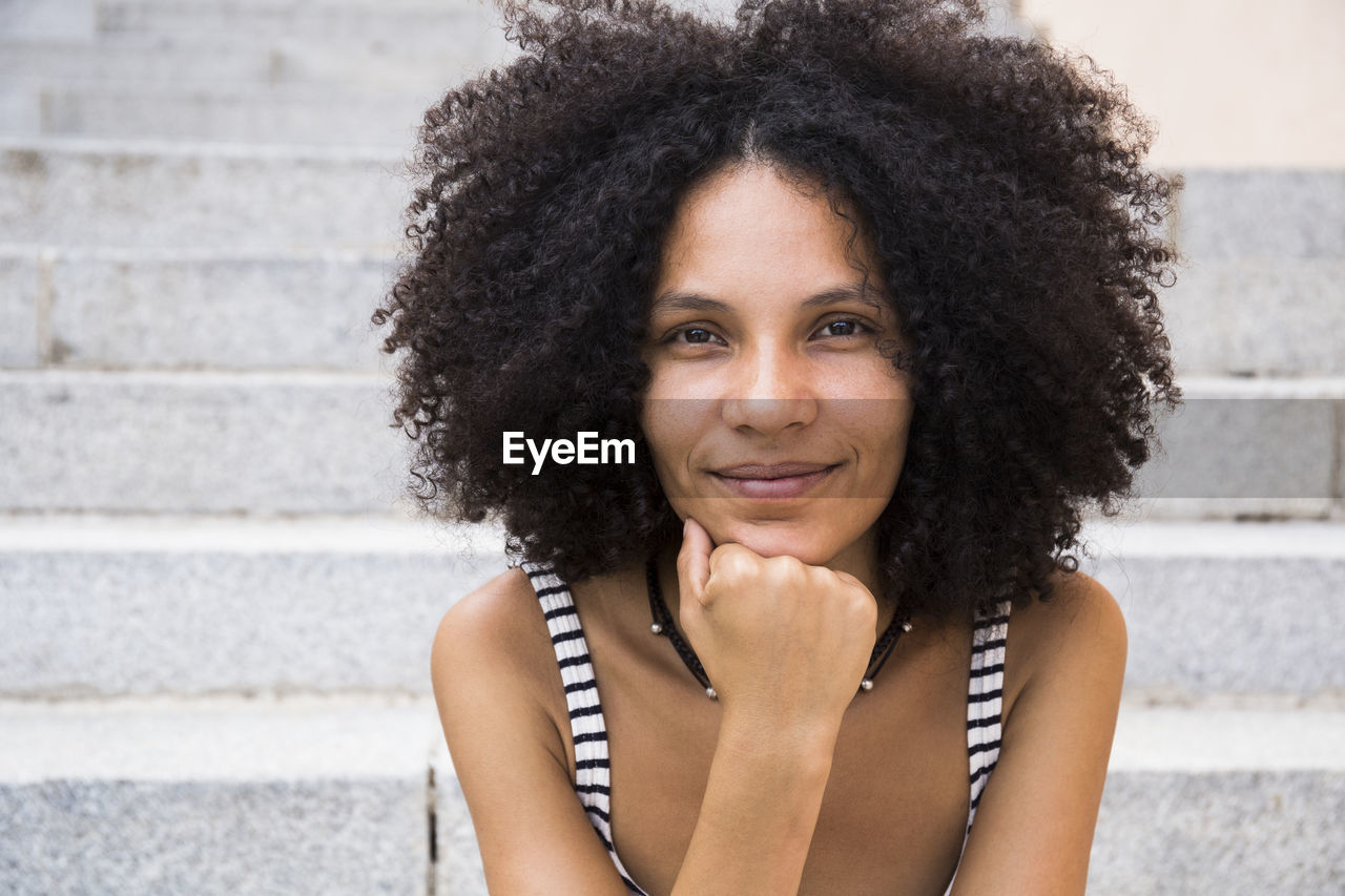 Portrait of smiling young woman sitting on stairs