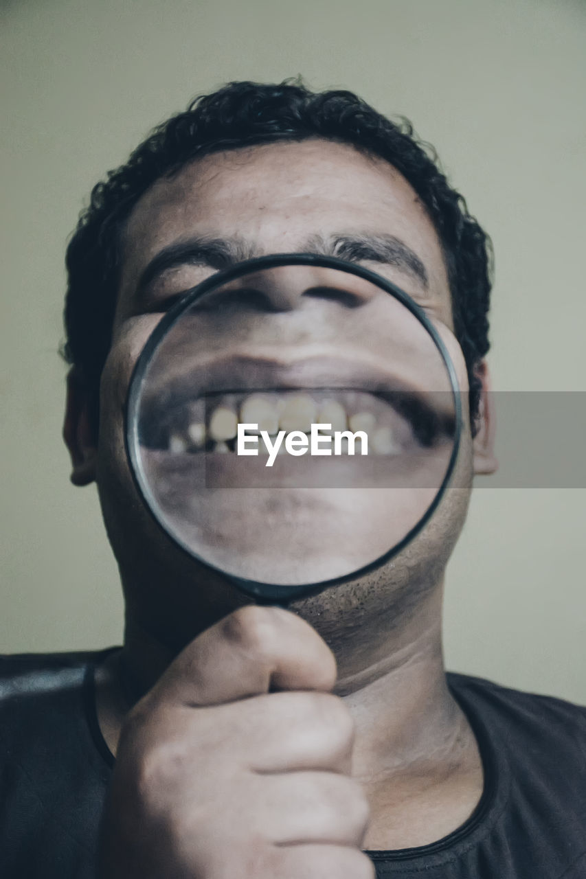 Close-up portrait of man with magnifying glass