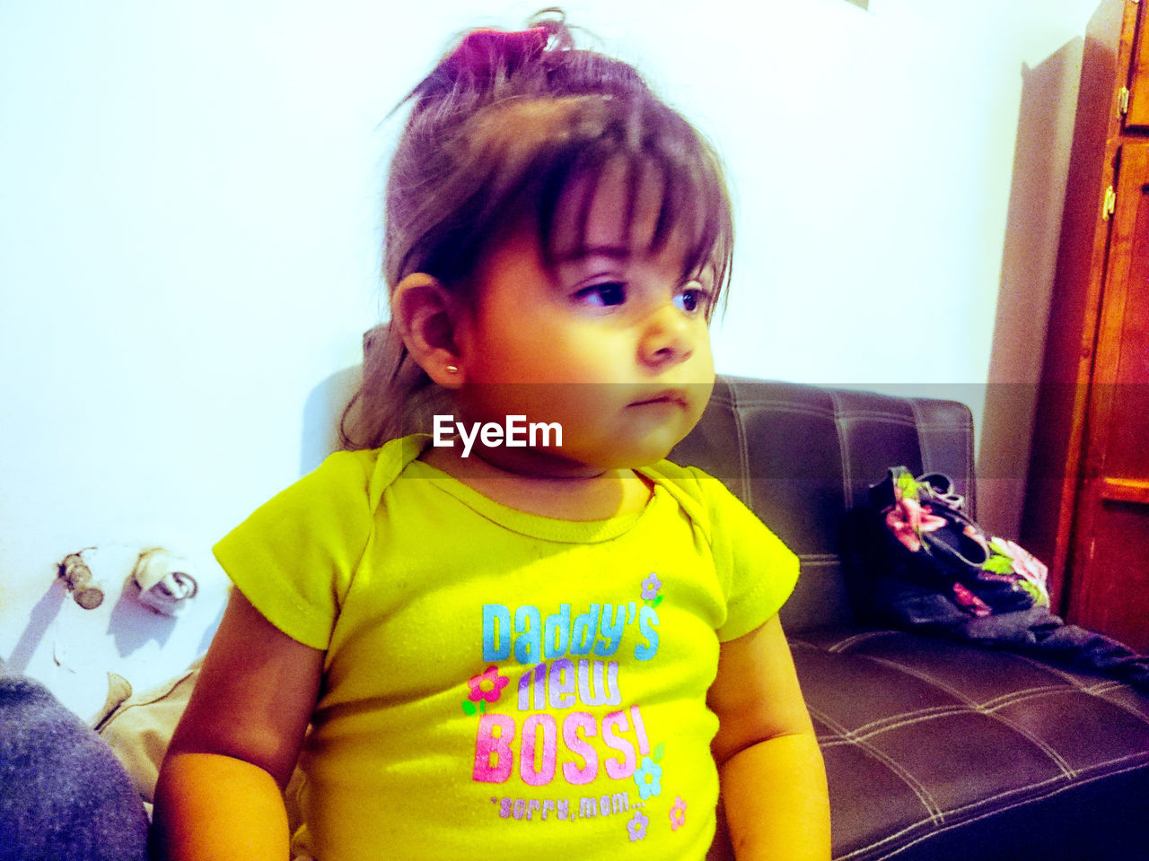 CUTE BOY LOOKING AWAY WHILE SITTING ON SOFA AT HOME
