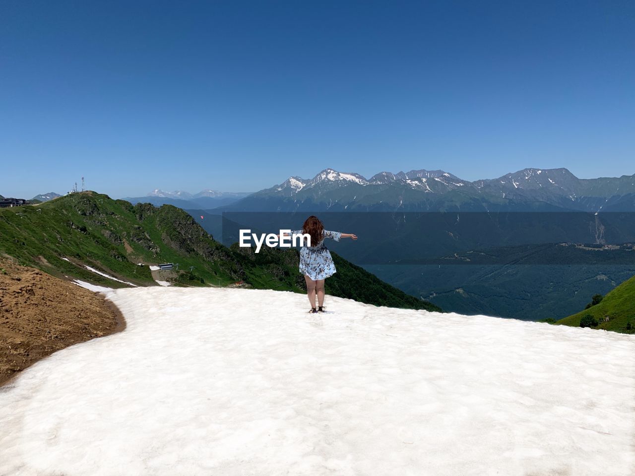 Rear view of woman standing on snow against mountain and sky