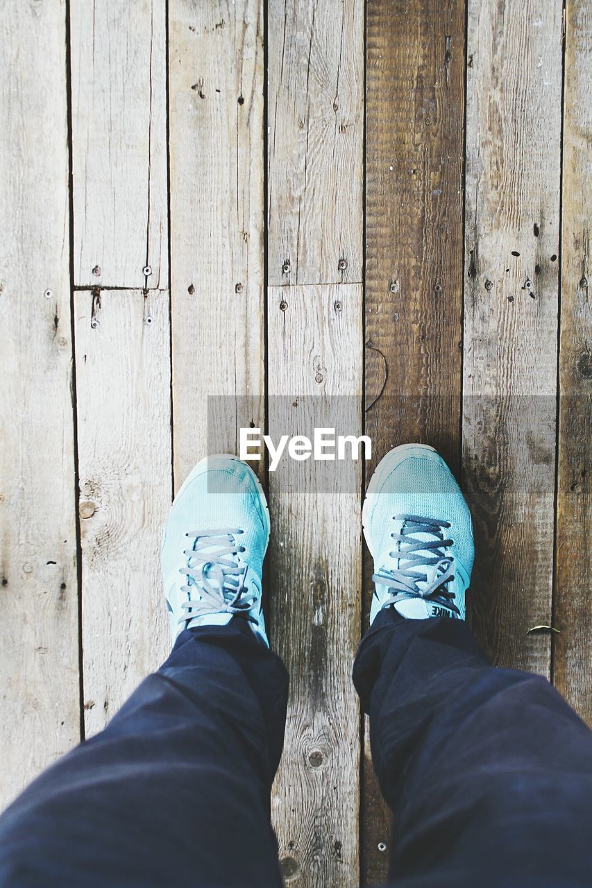 Low section of person standing on wooden floor