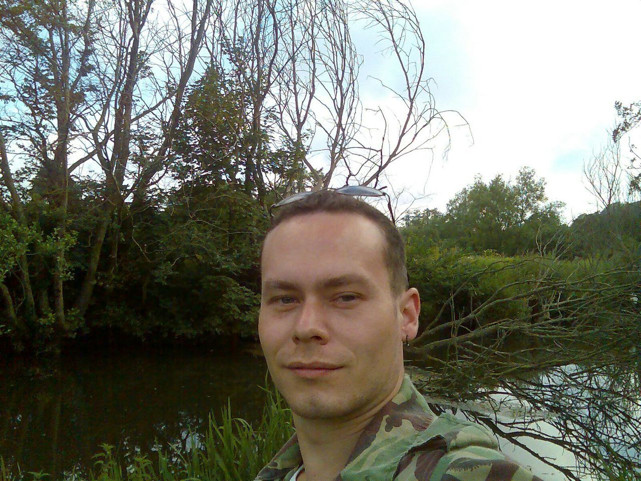 Portrait of young man by stream in forest