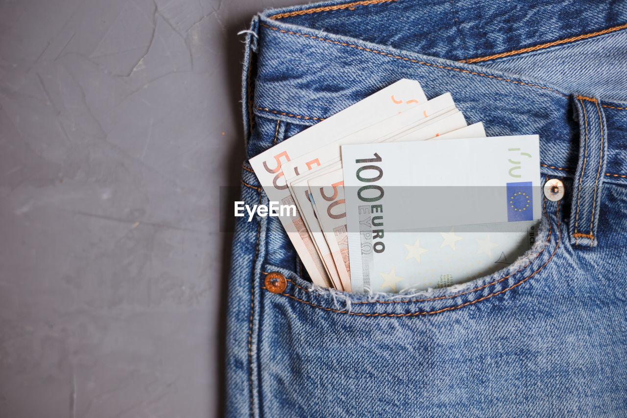 Directly above shot of paper currencies in jeans pocket on gray background