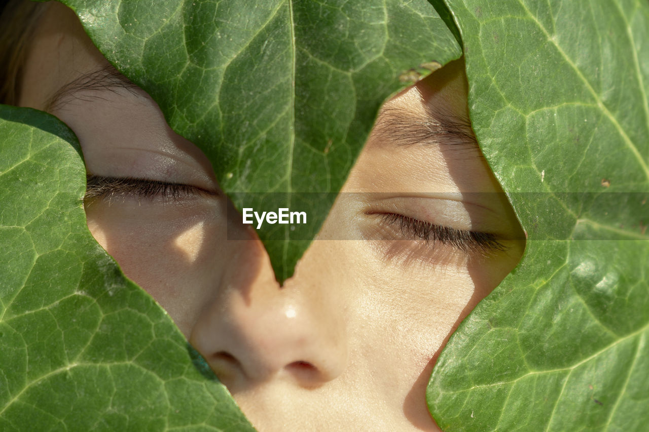 Close-up of girl with leaves and eyes closed