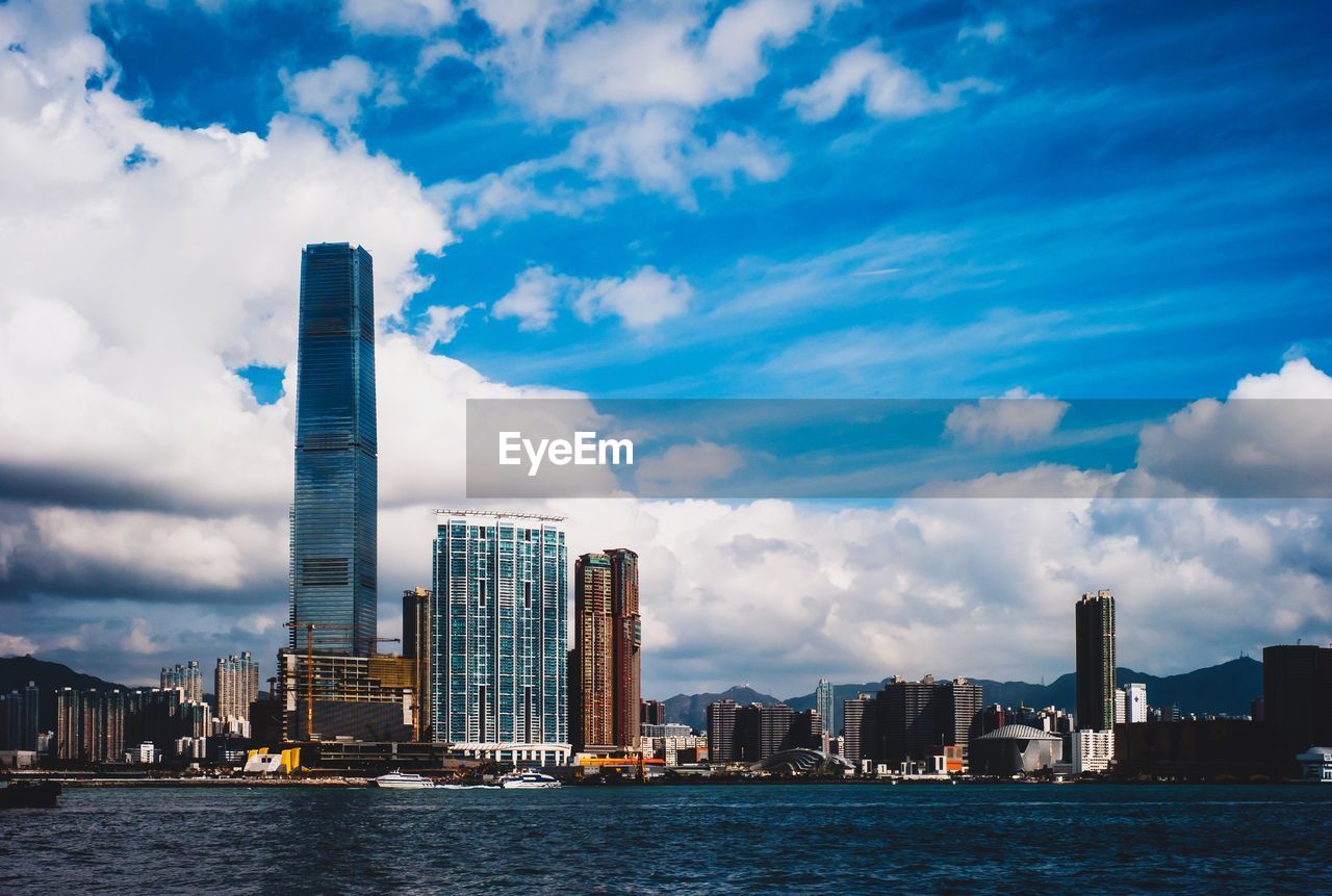 Sea by modern buildings against sky in city