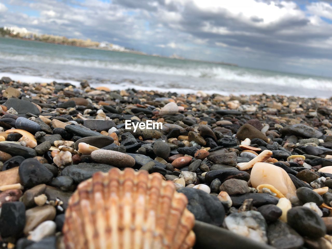 Close-up of pebbles on beach against cloudy sky