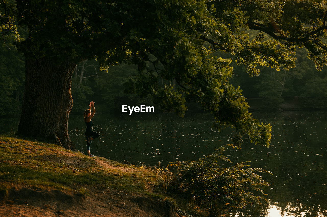 Side view of woman exercising by lake