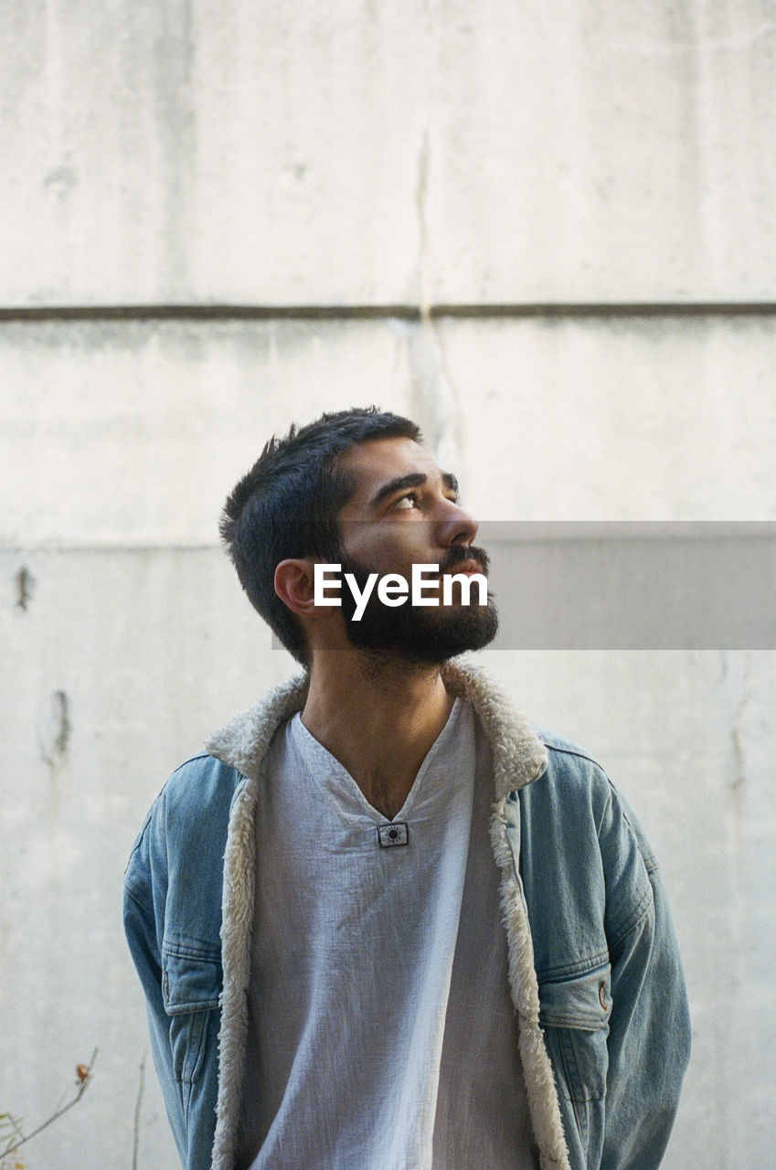 MAN LOOKING AWAY AGAINST WALL