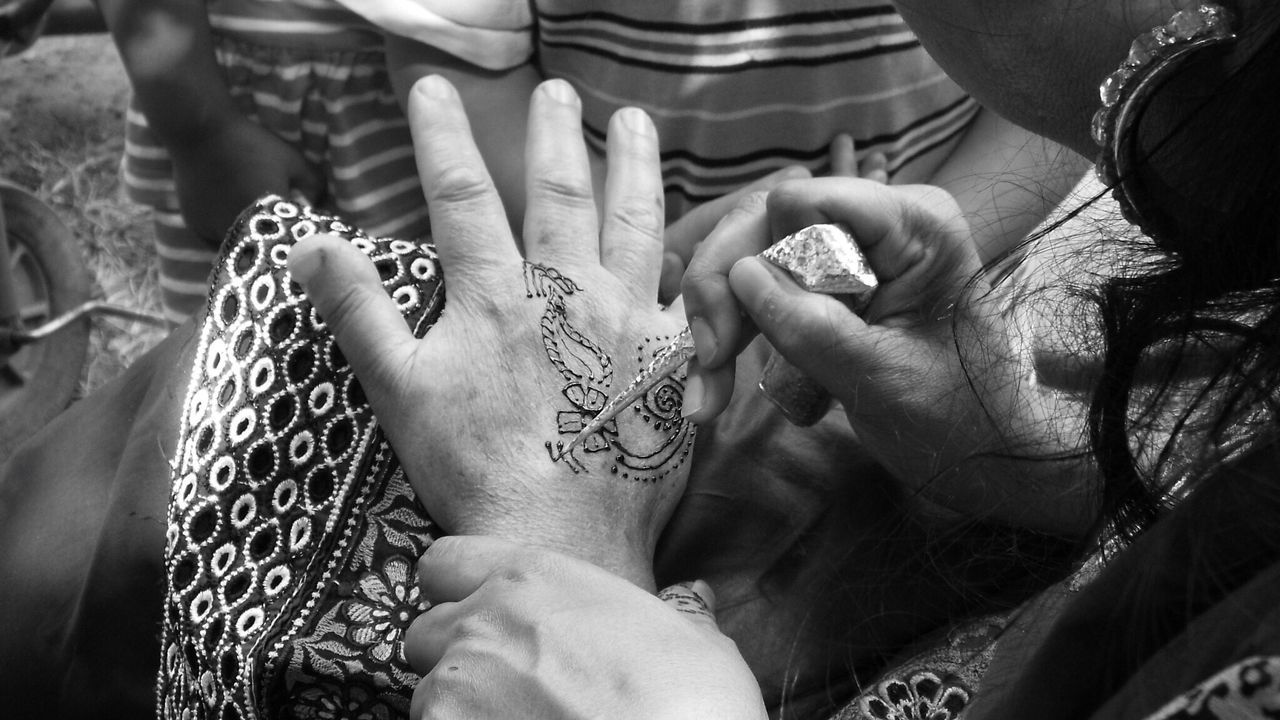 Woman drawing henna tattoo on hand