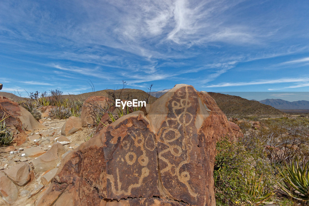 Rocks on mountains against cloudy sky