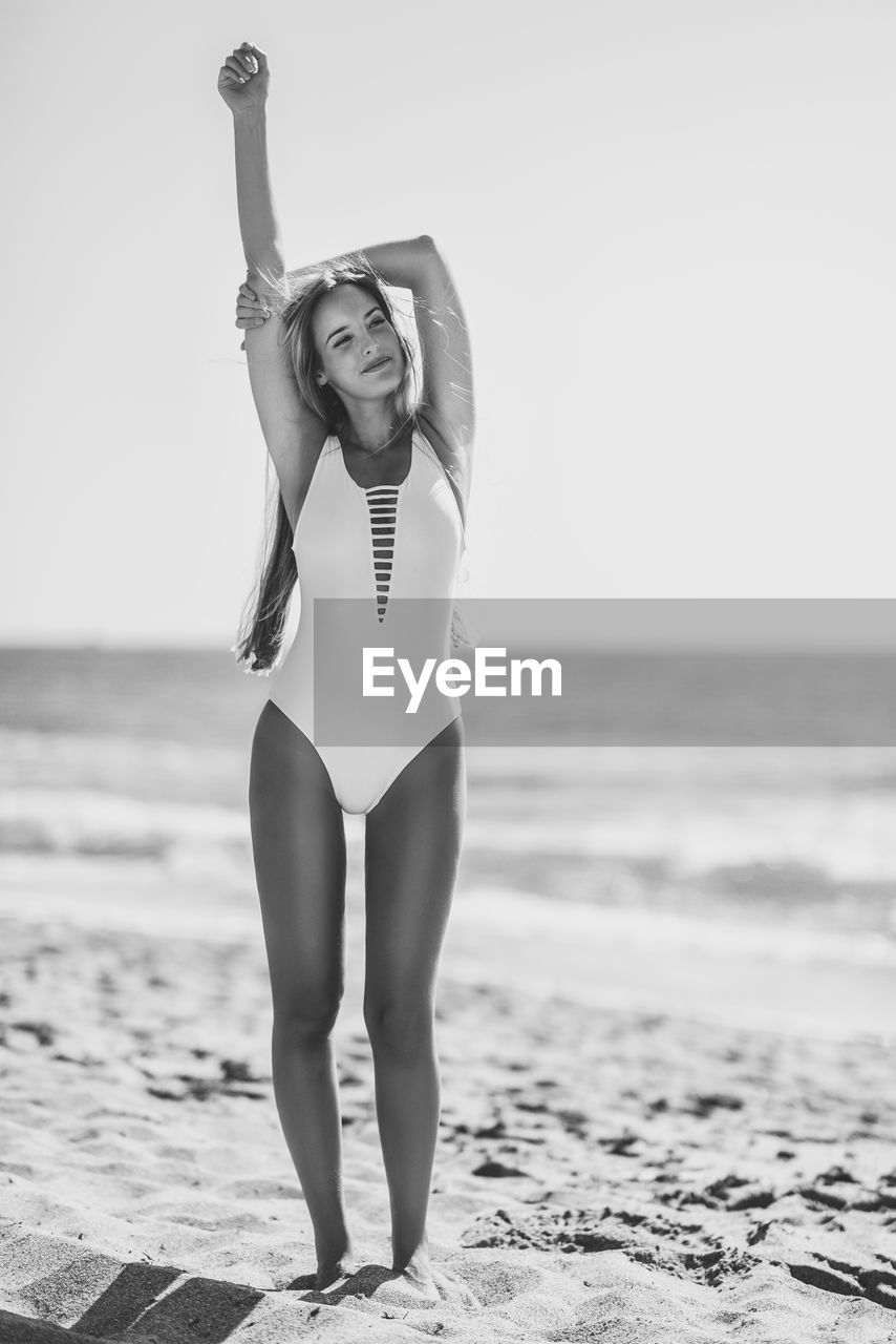 Sensuous woman in swimsuit standing at beach