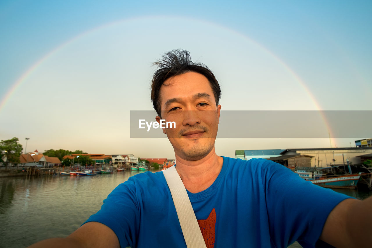 Portrait of mid adult man against rainbow sky