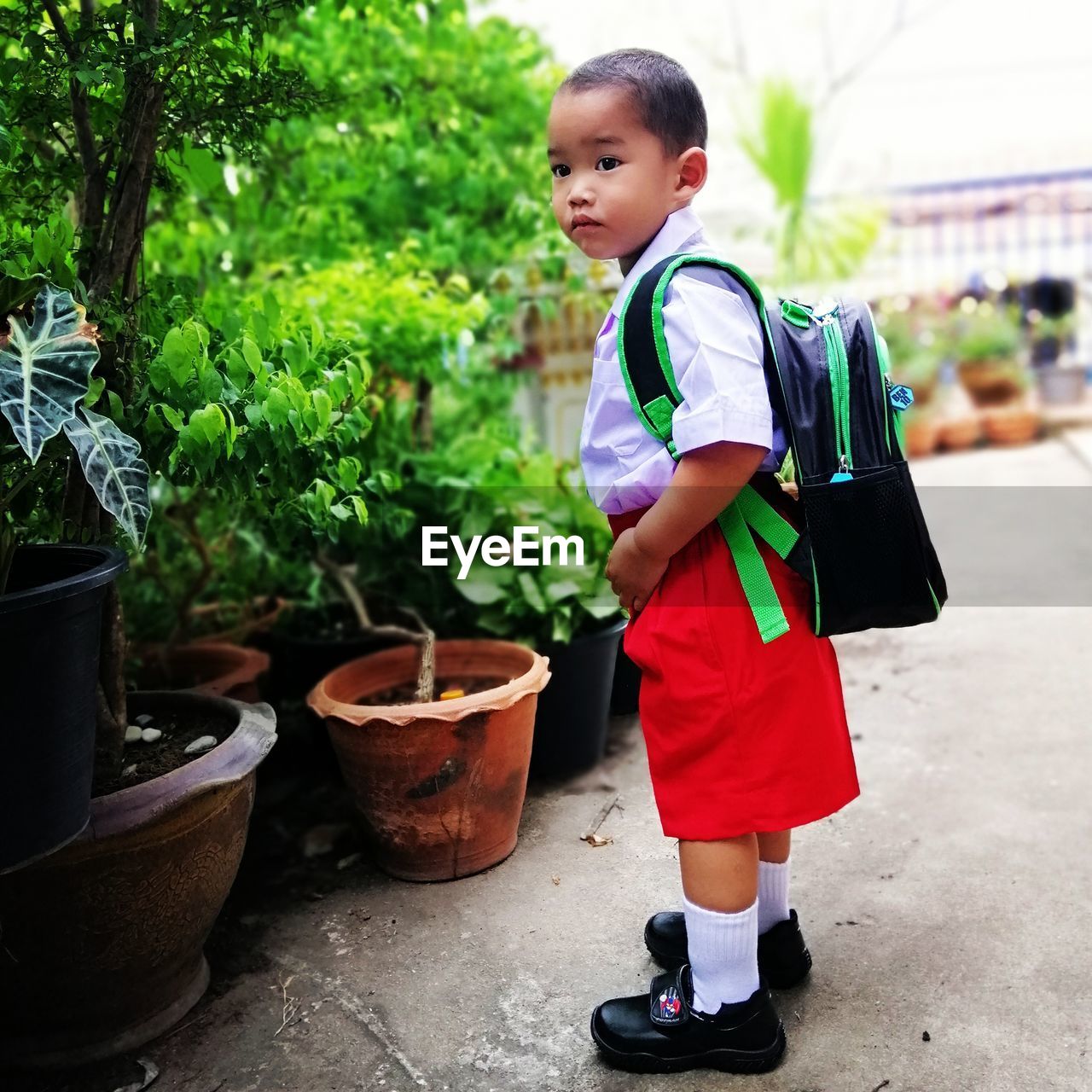 Side view of boy wearing uniform standing on footpath