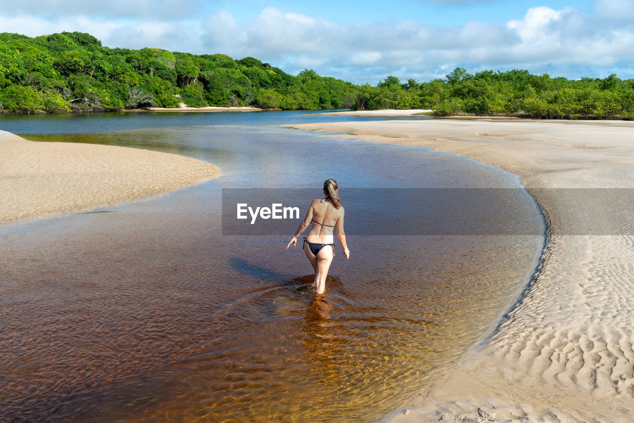 Young beautiful woman walking inside the reddish water. 