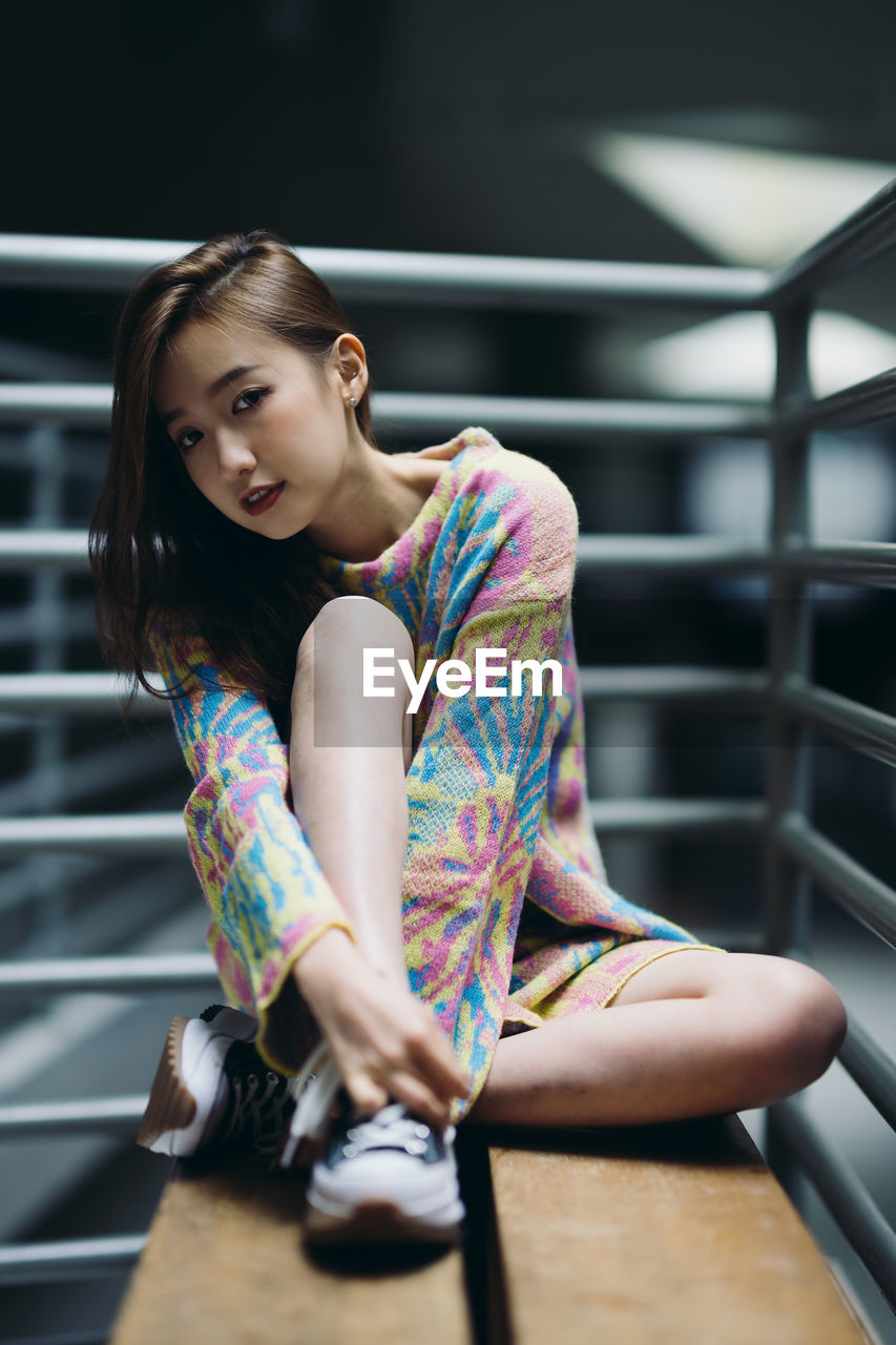 portrait of young woman looking away while sitting in gym