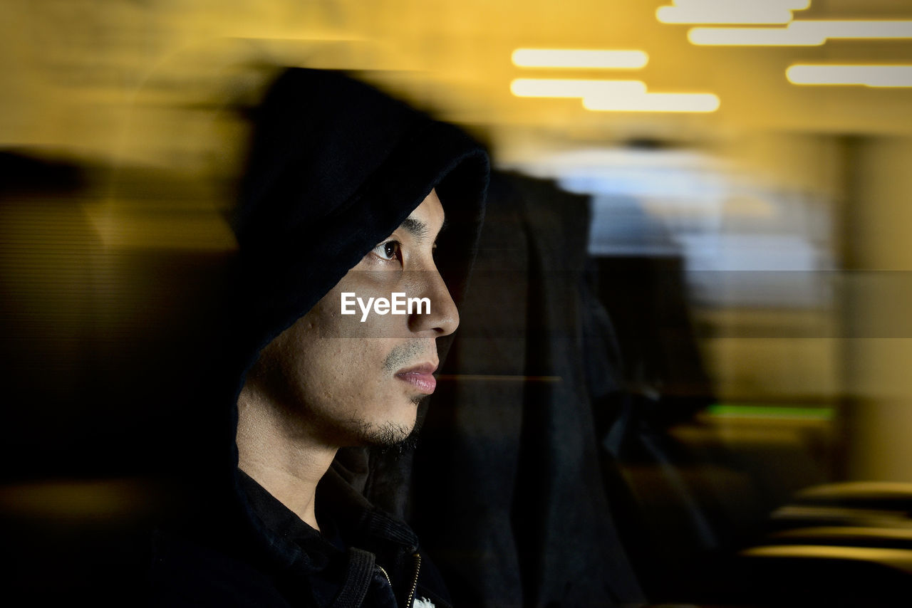 Close-up of man wearing hood seen through glass