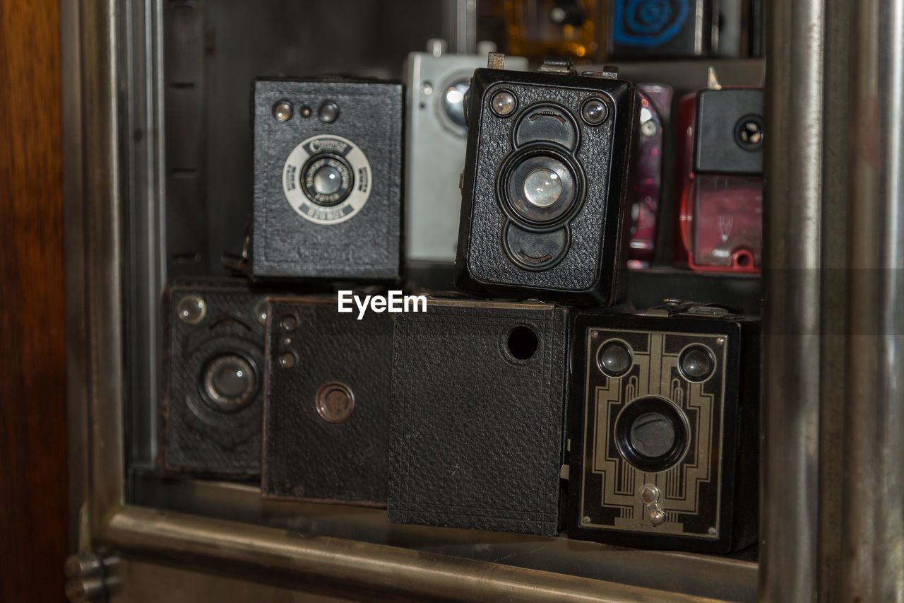 Old vintage box cameras stored in a wooden shelf.