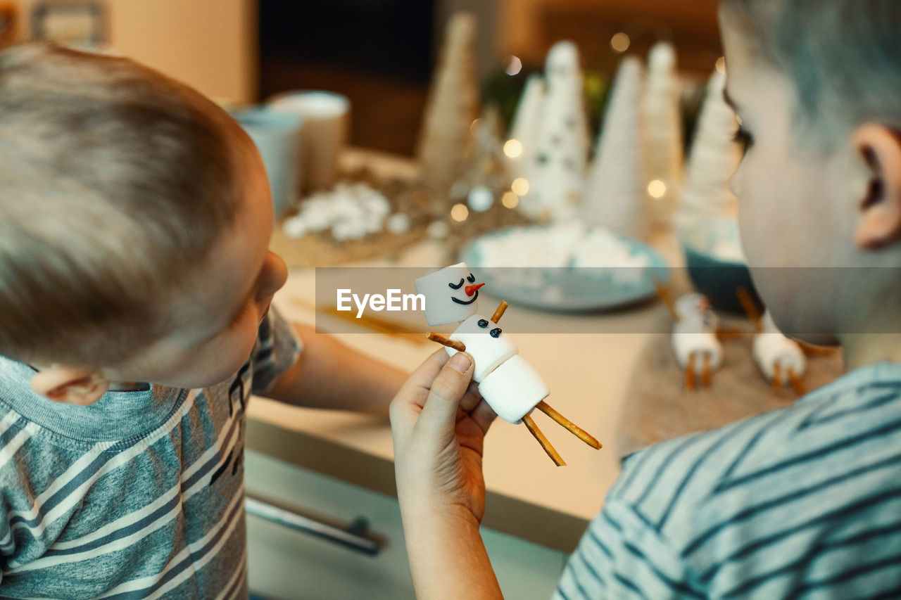 Cropped image of boy holding marshmallow at home