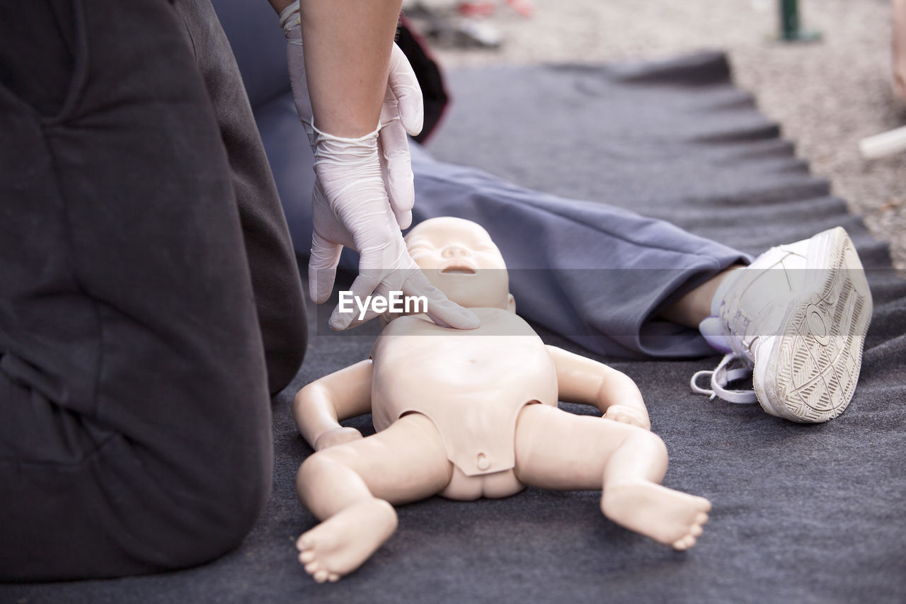 Midsection of paramedics performing cpr on baby mannequin