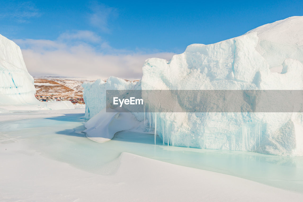 Village of qaanaaq behind icebergs, greenland.