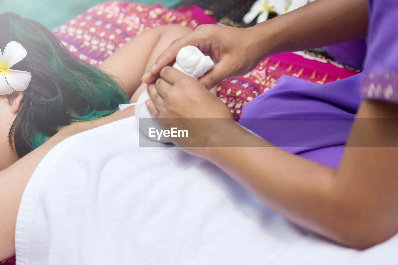 Cropped hands of masseur massaging woman in spa