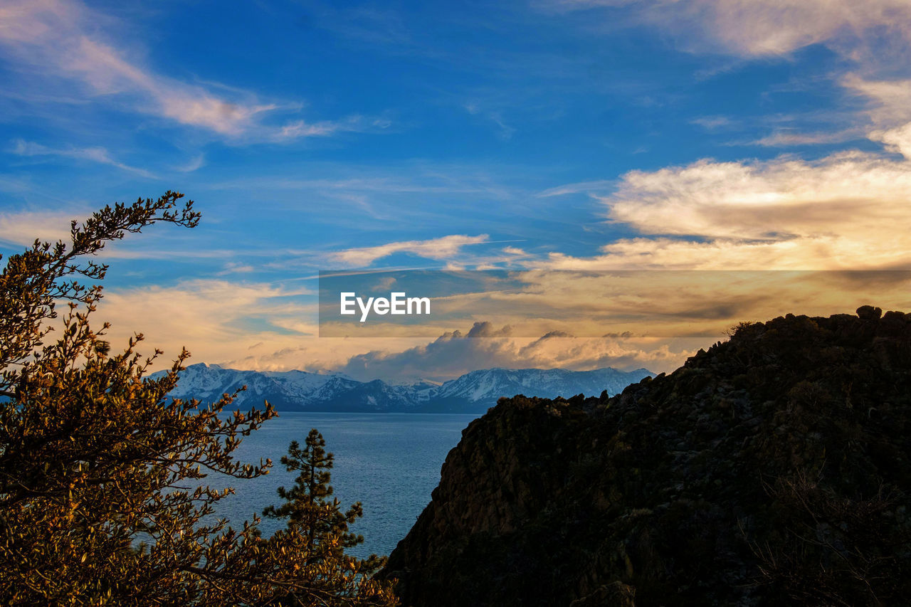 SCENIC VIEW OF SEA AND SILHOUETTE MOUNTAINS AGAINST SKY