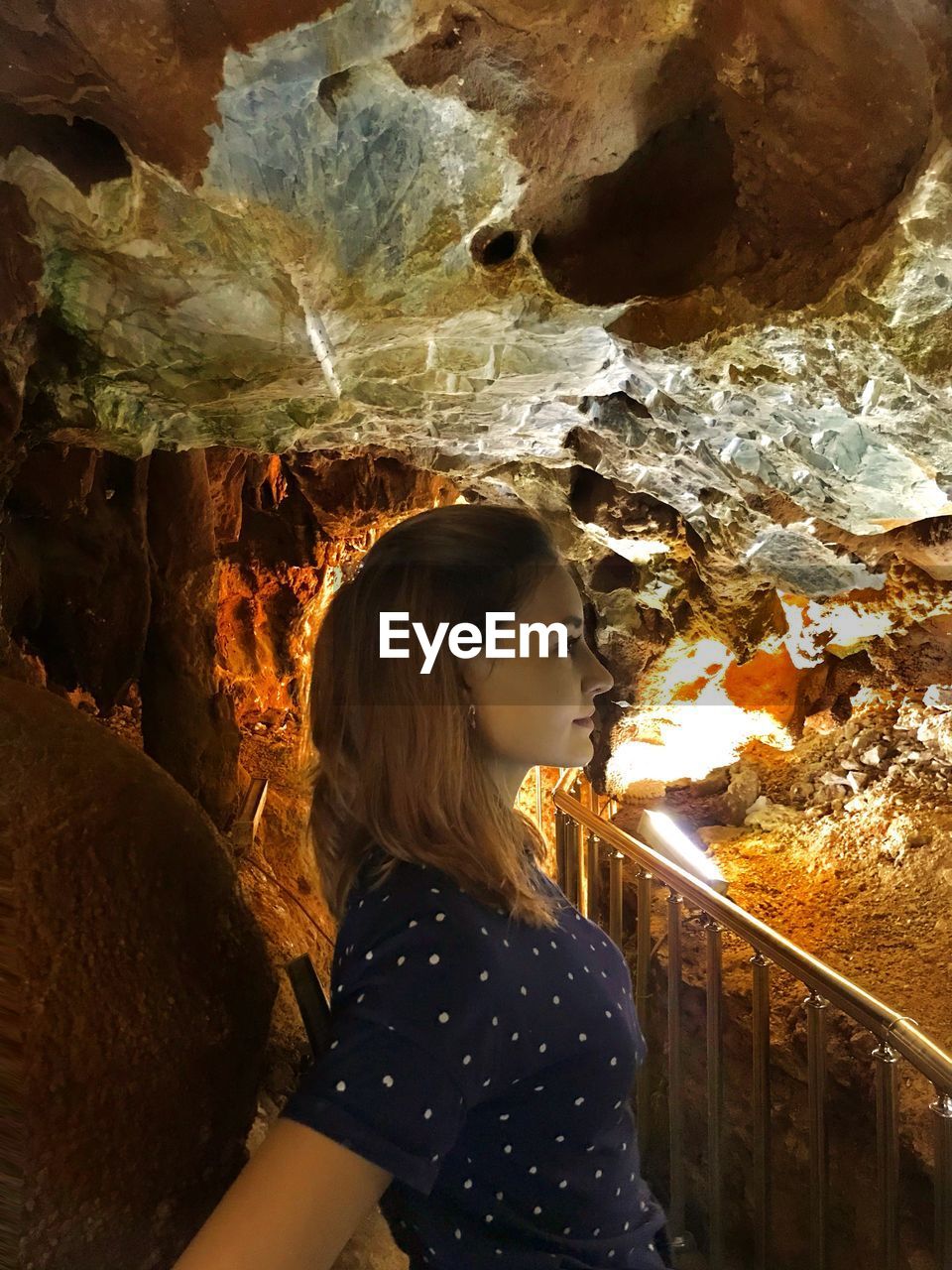 Side view of woman looking away while standing in cave